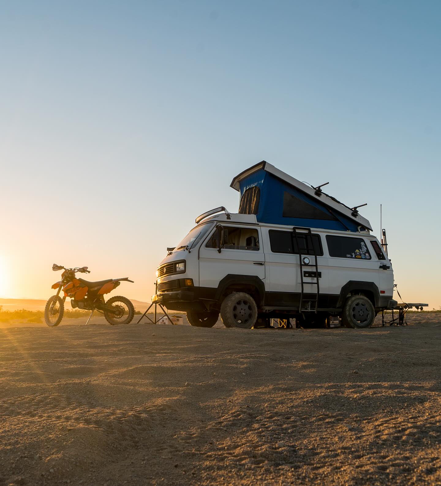 Westfalia and motorcycle parked at sunset