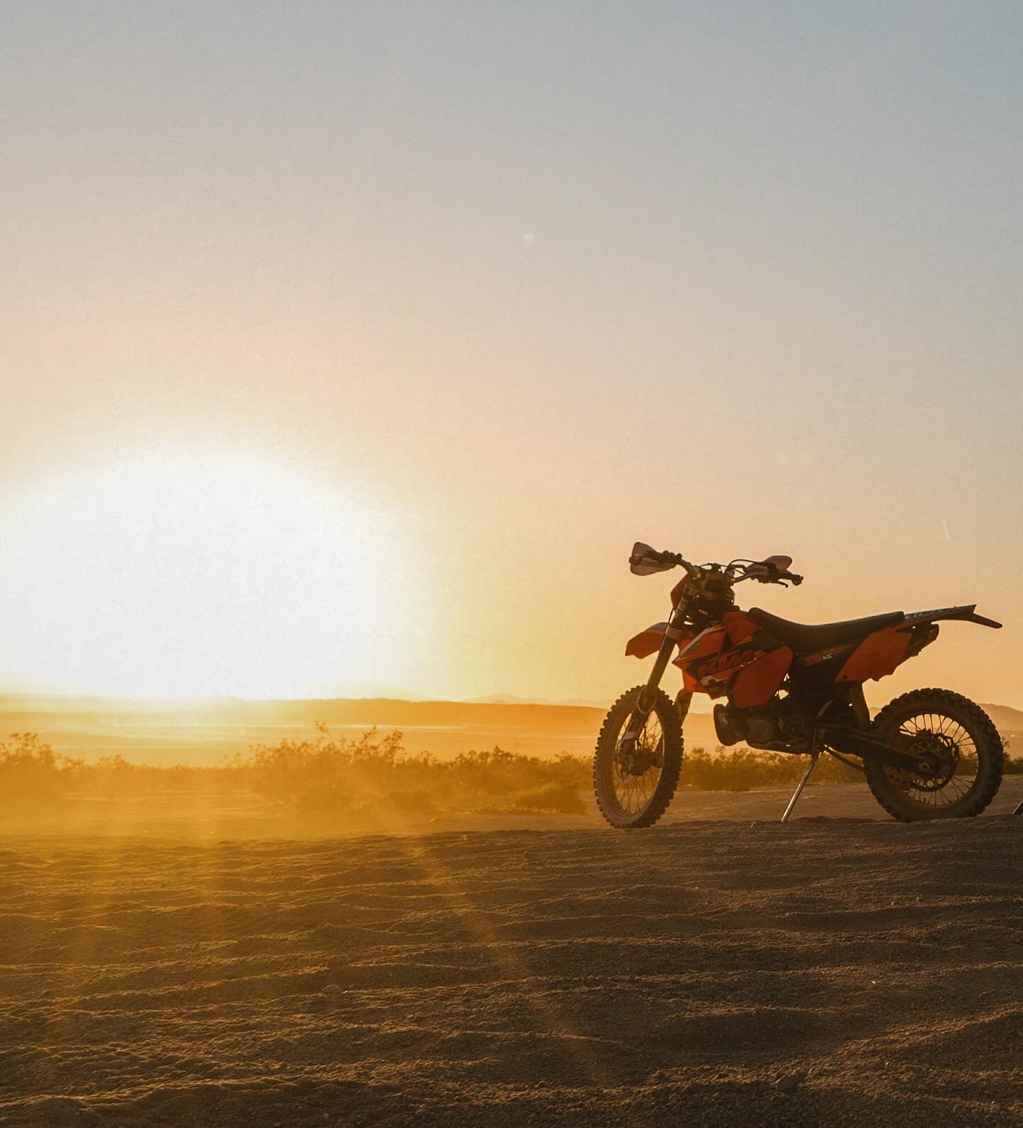 Motorcycle parked near camp at sunset